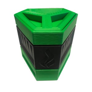 May include: A geometric, three-tiered container with a green top and bottom and a black center section. The black section features a flame-like design. The container has a unique, angular shape.