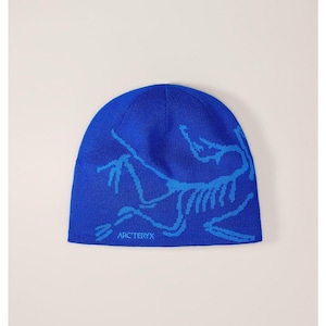 May include: A blue beanie featuring a light blue graphic design and the text "ARC'TERYX". The hat is made of a soft, knitted material. It is designed to keep the head warm.