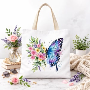 May include: White tote bag with a watercolor design of a blue and purple butterfly and a bouquet of pink and yellow flowers. The bag has beige handles and is sitting on a white surface.