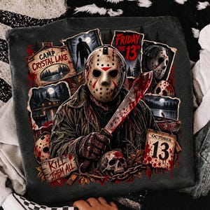 May include: A dark gray t-shirt featuring a graphic print of a hockey-masked figure holding a machete. The design includes text reading Camp Crystal Lake, Friday the 13th, Kill Them All, and October 13, alongside imagery of a skull, a cabin, and a lake.