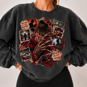 May include: A charcoal gray crewneck sweatshirt featuring a graphic print of a horror movie character with a clawed hand, a fedora, and a red and black striped sweater. The design includes text reading Welcome to your nightmare, Elm St., and Never sleep again.