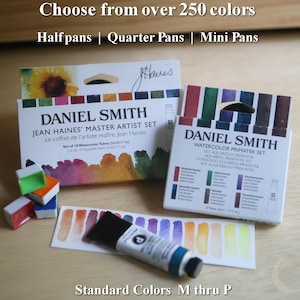 Puede incluir: Juegos de pintura de acuarela Daniel Smith. La imagen muestra dos cajas de pinturas de acuarela, un tubo de pintura y varias muestras de pintura pequeñas. El texto en las cajas dice "Jean Haines' Master Artist Set" y "Watercolor Primatek Set". La imagen también incluye el texto "Elige entre más de 250 colores".