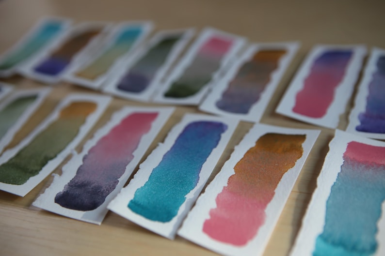 Swatches of the Da Vinci Tropical Palette which includes 6 half pans of the following colors: Sage & Amber, Joyce's Mother Violet, Denise's New Green, Artemis, Seaglass, Da Vinci Red Tint
