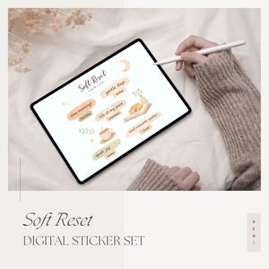 May include: A digital sticker set titled "Soft Reset" displayed on a tablet. The stickers feature watercolor illustrations and text like "slow mornings," "gentle days," and "quiet joy." The image includes a stylus and the text "DIGITAL STICKER SET."