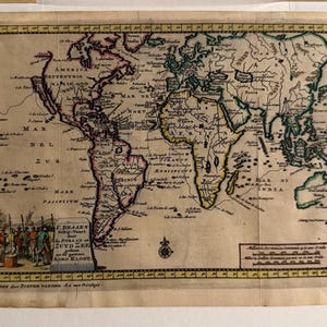 May include: An old world map, showing continents and oceans with detailed illustrations. The map includes text in various languages, a decorative border, and a scene of people and ships in the bottom left. Printed on aged paper, it has a vintage feel.