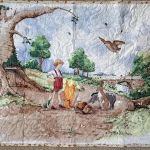 May include: A quilted blanket with a storybook illustration. The scene shows a young person in red overalls with a bear, donkey, and pig. A bridge, trees, and an owl are also visible. The blanket has a patterned border.