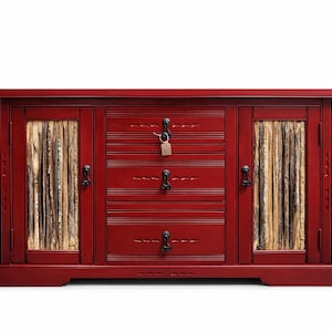 Könnte beinhalten: Ein roter Holzschrank mit drei Schubladen und zwei Türen. Die Türen haben ein natürliches Holzpaneel-Design. Der Schrank hat schwarze Beschläge und ein Schlüsselschloss an der mittleren Schublade. Der Schrank ist im rustikalen Stil gehalten.