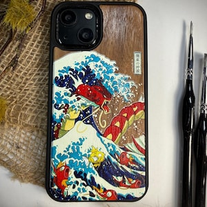 Könnte beinhalten: Eine Handyhülle aus Holz mit einem Design, das von dem japanischen Kunstwerk "Die große Welle vor Kanagawa" inspiriert wurde. Die Hülle hat einen schwarzen Rand, eine braune Holzmaserung und eine lebendige Illustration einer Welle mit roten und gelben Kreaturen.
