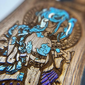 K&ouml;nnte beinhalten: Nahaufnahme einer Holzoberfl&auml;che mit einer detaillierten Gravur einer Figur mit blauen Haaren und Akzenten. Das Kunstwerk zeigt komplizierte Designs und eine Mischung aus hellen und dunklen Holzt&ouml;nen, die einen auff&auml;lligen visuellen Kontrast erzeugen. Die Figur ist mit blauen wolkenartigen Details verziert.