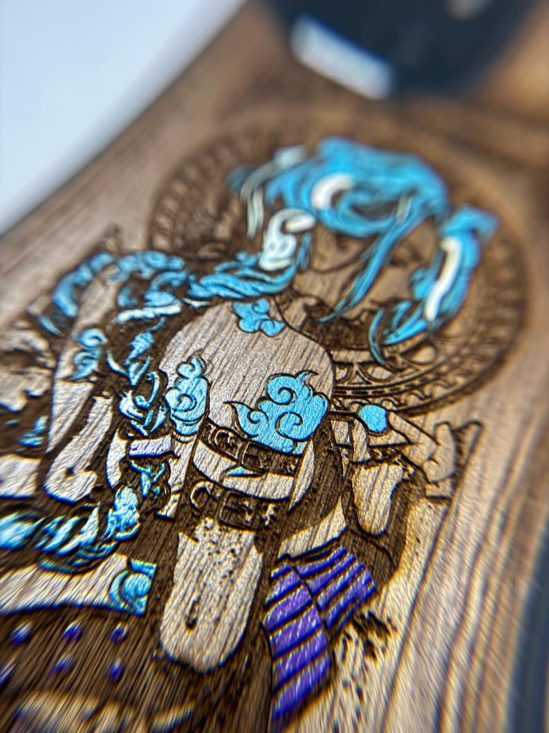 K&ouml;nnte beinhalten: Nahaufnahme einer Holzoberfl&auml;che mit einer detaillierten Gravur einer Figur mit blauen Haaren und Akzenten. Das Kunstwerk zeigt komplizierte Designs und eine Mischung aus hellen und dunklen Holzt&ouml;nen, die einen auff&auml;lligen visuellen Kontrast erzeugen. Die Figur ist mit blauen wolkenartigen Details verziert.