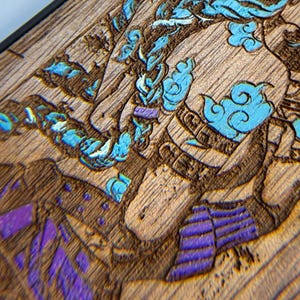K&ouml;nnte beinhalten: Nahaufnahme einer Holzschnitzerei mit detailliertem Design. Das Kunstwerk zeigt eine Figur mit blauen und violetten Akzenten, vor einem Hintergrund aus nat&uuml;rlicher Holzmaserung. Die Schnitzerei ist schwarz umrahmt.