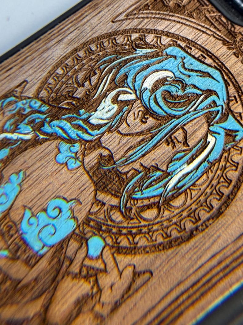 K&ouml;nnte beinhalten: Nahaufnahme einer Holzoberfl&auml;che mit detailliertem Laser-&Auml;tz-Design. Das Design zeigt eine blau-wei&szlig;e Wasserkreatur in einem kreisf&ouml;rmigen Rahmen. Das Holz hat einen nat&uuml;rlichen Braunton, und das Design ist aufwendig geschnitzt.