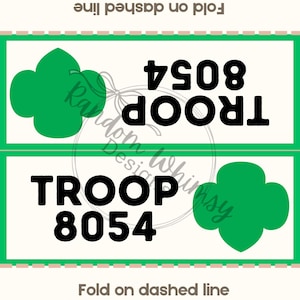 May include: Two rectangular cards with green borders and a cream background. Each card features a green clover graphic and the text "TROOP 8054" in bold black font. The text "Fold on dashed line" is also present.
