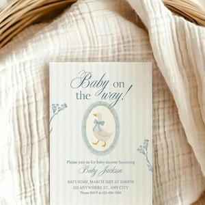 May include: A rectangular baby shower invitation card with a light blue striped background, featuring a central oval frame containing a white duck with a blue bow. The text reads: Baby on the way! Please join us for baby shower honoring Baby Jackson, Saturday, March 31st at 2:00PM, 123 Anywhere St., Any City, Please RSVP at 123-456-7890.