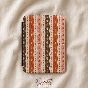 May include: A rectangular e-reader case featuring a repeating vertical pattern of wavy stripes in shades of brown, orange, and cream. The design includes small illustrations of mushrooms, leaves, and stars arranged in columns across the surface.
