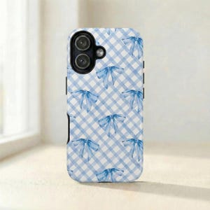 Pode incluir: Capa de telemóvel com um padrão xadrez vichy azul e branco, adornada com laços azuis em aquarela. A capa tem um acabamento brilhante e um recorte para a câmara.