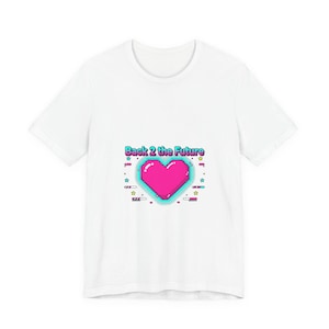 Puede incluir: Camiseta blanca con un diseño retro. Presenta un corazón rosa pixelado con un contorno turquesa y el texto "Back 2 the Future". El diseño incluye estrellas y barras, creando una estética nostálgica inspirada en los años 80.