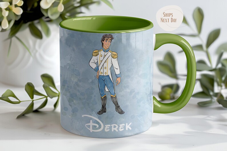 May include: A ceramic mug with a green handle and interior. The mug features a watercolor illustration of a prince in a white and gold uniform, with blue pants. The name "Derek" is printed on the mug.