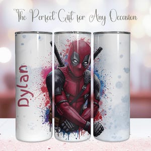 K&ouml;nnte beinhalten: Ein wei&szlig;er Becher mit einem Deadpool-Design in Rot und Schwarz. Der Becher hat einen Spritzer roter, blauer und violetter Farbe. Der Name "Dylan" ist auf der Seite aufgedruckt. Der Text "The Perfect Gift for Any Occasion" steht oben.