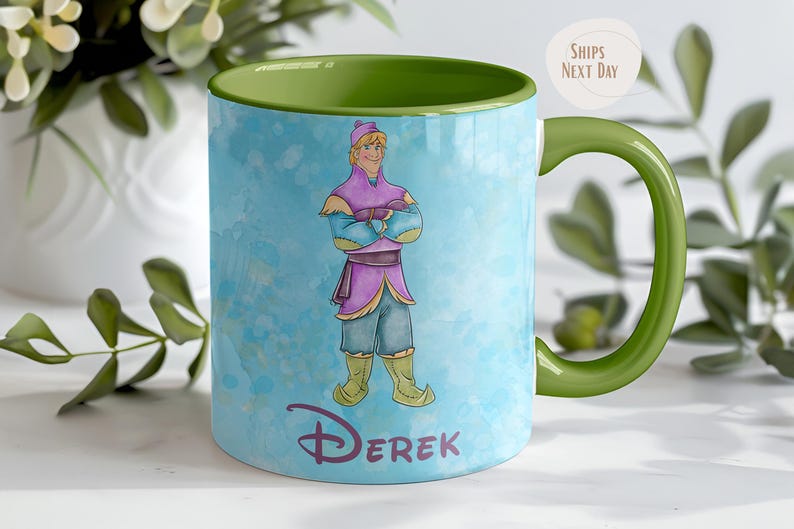 Peut inclure: Mug en c&eacute;ramique avec une anse et un int&eacute;rieur verts. La tasse pr&eacute;sente une illustration &agrave; l'aquarelle d'un personnage de dessin anim&eacute; v&ecirc;tu d'une tenue violette et bleue. Le nom "Derek" est imprim&eacute; en violet.