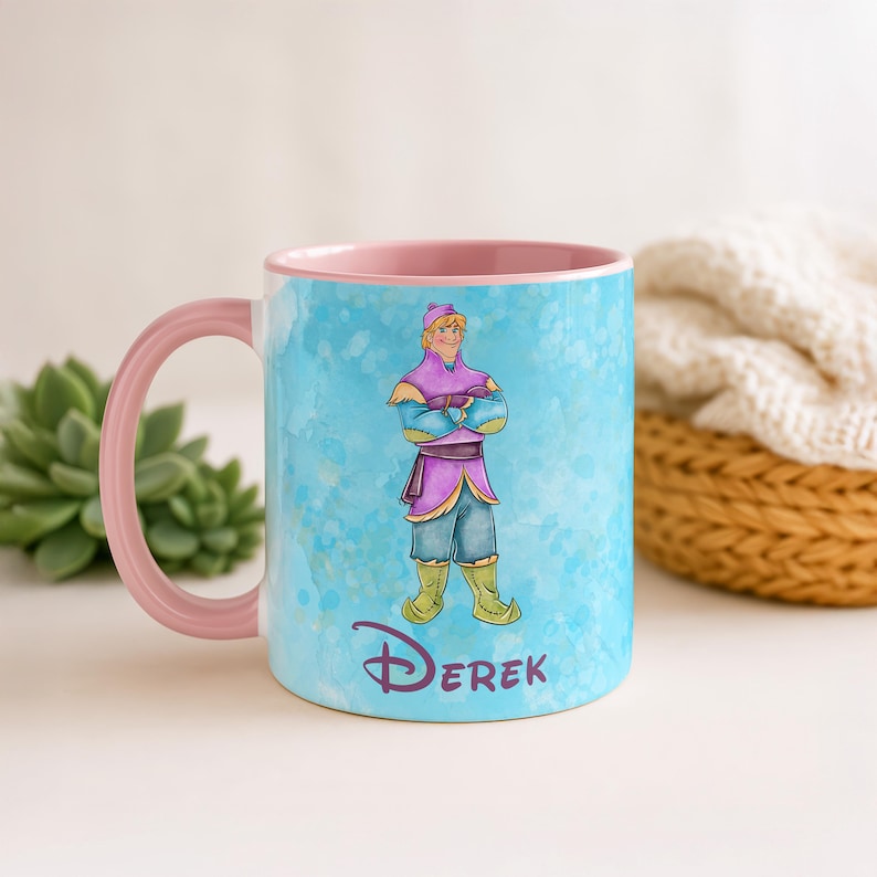 Peut inclure: Une tasse en c&eacute;ramique avec une anse et un int&eacute;rieur roses. L'ext&eacute;rieur pr&eacute;sente une illustration &agrave; l'aquarelle d'un personnage en tenue violette et bleue, avec le nom "Derek" en &eacute;criture cursive. Le fond est bleu clair.