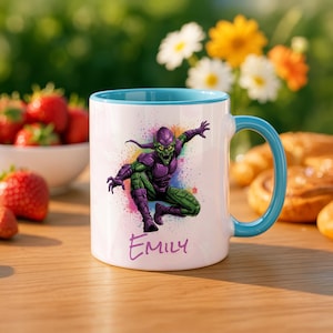 May include: White ceramic mug with a teal interior and handle. The mug features a colorful illustration of a comic book character in purple and green. The name "Emily" is written in cursive below the character.