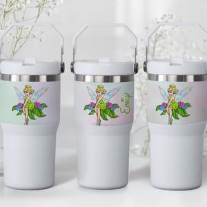 May include: Three white insulated tumblers with a handle. Each tumbler features a colorful illustration of a fairy with wings, green dress, and flowers. One tumbler has the name "Emily" in green script.