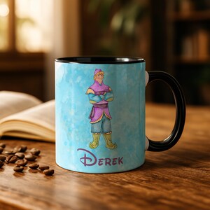 Peut inclure: Mug en c&eacute;ramique avec une anse et un int&eacute;rieur noirs. La tasse pr&eacute;sente une illustration de personnage sur un fond bleu clair avec le nom "Derek" en police Disney. Le personnage porte une tenue violette et bleue.