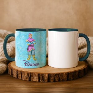 Peut inclure: Deux mugs en c&eacute;ramique blanche avec des poign&eacute;es et un int&eacute;rieur turquoise. L'un des mugs pr&eacute;sente une illustration de dessin anim&eacute; d'un personnage en tenue violette et bleue avec le nom "Derek" en dessous. L'autre mug est blanc uni.
