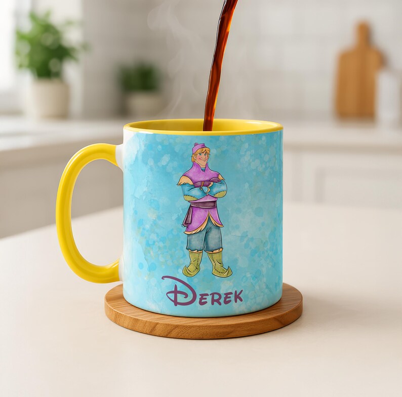 Peut inclure: Une tasse en c&eacute;ramique avec une anse et un int&eacute;rieur jaunes, repr&eacute;sentant une illustration de personnage en tenue violette et bleue. La tasse porte le nom "Derek" dans une police stylis&eacute;e et repose sur un dessous de verre en bois. Du caf&eacute; est vers&eacute; dans la tasse.