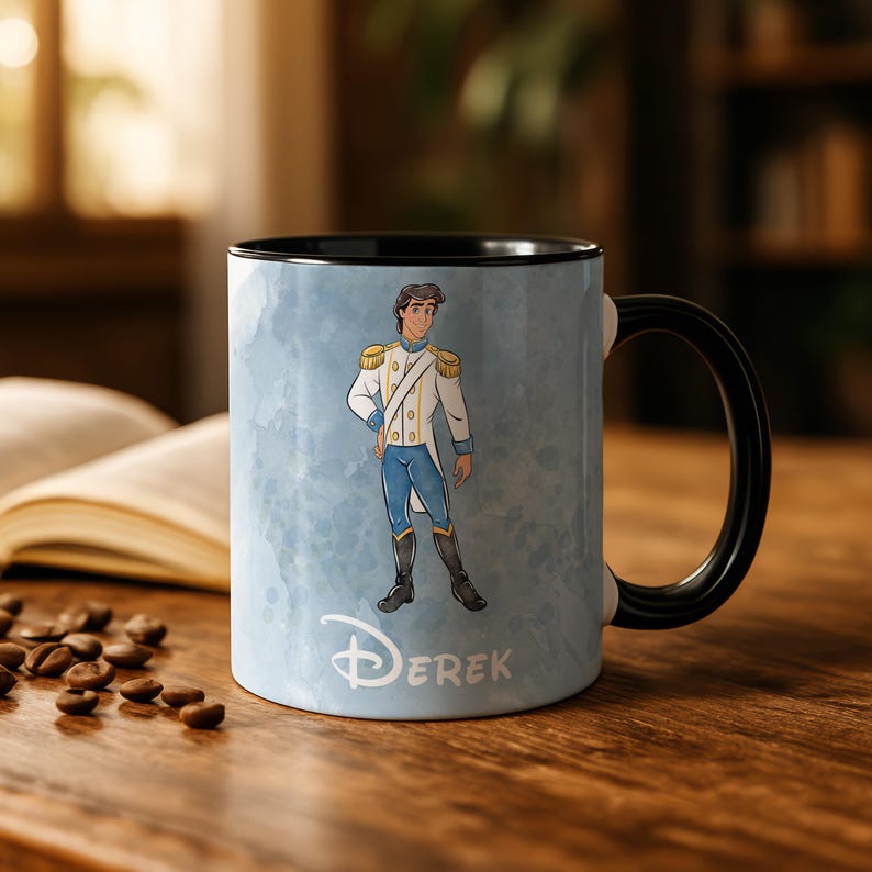 May include: A ceramic mug with a black handle and interior. The mug features a cartoon illustration of a prince in a white and blue outfit against a light blue watercolor background. The name "Derek" is printed below the illustration.