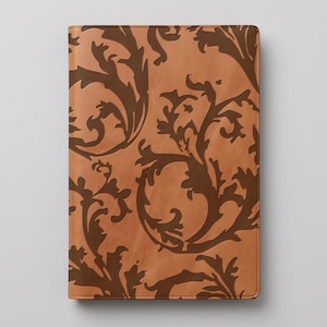 Può includere: Una copertina per taccuino rettangolare caratterizzata da una base color marrone chiaro con un intricato motivo floreale a vortice color marrone scuro. Il design copre l'intera superficie frontale, mostrando un motivo organico ripetuto con linee curve.