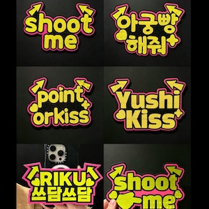 May include: A collection of six decorative stickers featuring yellow text with a honeycomb pattern, outlined in bright pink. The designs include phrases such as shoot me, point orkiss, Yushi Kiss, RIKU, and Korean characters, all accented with arrows and hearts.