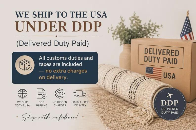 K&ouml;nnte beinhalten: Ein gerollter beiger Webteppich mit dunklen Streifen und Fransen, neben einem Karton mit der Aufschrift DELIVERED DUTY PAID USA und einer US-Flagge. Der Text enth&auml;lt WE SHIP TO THE USA UNDER DDP und All customs duties and taxes are included.