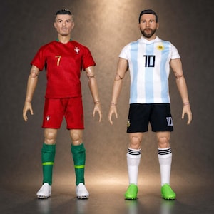 Pode incluir: Duas figuras de ação articuladas de jogadores de futebol. A figura da esquerda veste uma camisola vermelha com o número 7, calções vermelhos e meias verdes. A figura da direita veste uma camisola às riscas brancas e azul-claras com o número 10.