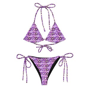 Peut inclure: Un ensemble bikini deux pièces arborant un motif floral violet et lavande éclatant sur fond clair. Le haut est de style triangle avec des liens réglables au cou et au dos. Le bas est doté de liens latéraux pour un ajustement personnalisé.