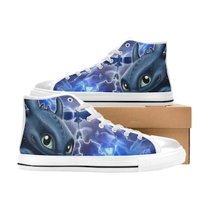 May include: High-top canvas trainers with a blue and white design featuring a cartoon dragon illustration. The trainers have white laces, a white rubber toe cap, and a white sole. The dragon design is set against a background of blue lightning.
