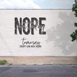 Puede incluir: Una pared de ladrillo blanco con las palabras "NOPE not today" y "tomorny doesn't look good either" en letras negras. Una calle, una acera y un árbol están en primer plano.