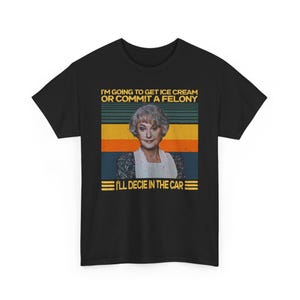 May include: Black t-shirt with a graphic featuring a woman and the text "I'M GOING TO GET ICE CREAM OR COMMIT A FELONY. I'LL DECIE IN THE CAR." The design includes a retro color scheme of orange, blue, and yellow stripes.