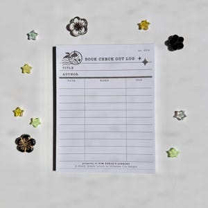 Pode incluir: Um livro branco de registro de empréstimo com o texto "BOOK CHECK OUT LOG" e campos para título, autor, data, nome e data de vencimento. O registro é cercado por pequenos enfeites decorativos em forma de flor e estrela em várias cores.