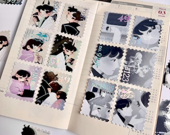 May include: A collection of decorative stickers resembling postage stamps, featuring illustrations of anime-style characters in various poses. The stickers are scattered on an open planner, with a metal clip holding the pages together.