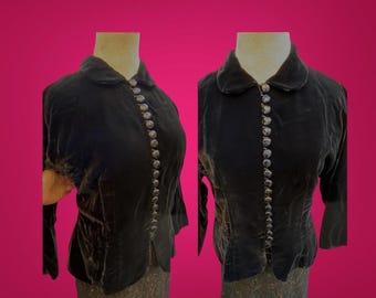 May include: A black velvet jacket with a Peter Pan collar and a row of decorative buttons down the front.