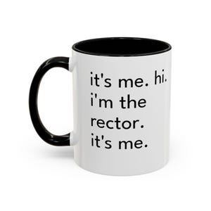 May include: White ceramic mug with a black handle and interior. The mug features the text "it's me. hi. I'm the rector. it's me." in black, centered on the front. The mug is designed for hot beverages.