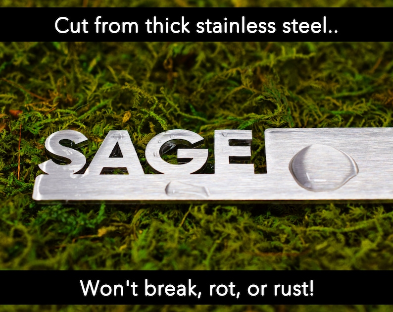 May include: A silver metal sign with the word "SAGE" cut out. The sign is on a bed of green moss. The text "Cut from thick stainless steel... Won't break, rot, or rust!" is visible above and below the sign.