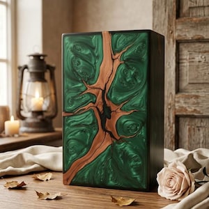 Pode incluir: Uma caixa retangular com um painel frontal apresentando um acabamento em resina verde esmeralda e uma incrustação central de veios de madeira natural. As laterais da caixa são pretas sólidas e a superfície é lisa e polida.