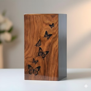 May include: A rectangular wooden box with a rich, brown wood grain finish. The box is adorned with a series of black butterfly silhouettes of varying sizes, creating a decorative pattern. The side of the box is a dark gray color.