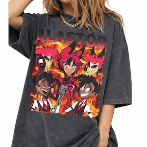 May include: Dark gray oversized t-shirt featuring a graphic of cartoon characters with the word "ALASTOR" across the top. The graphic includes characters in red, black, and white against a fiery background. The shirt has short sleeves.