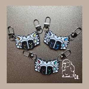 May include: Three butterfly-shaped keychains with black and white wings, each featuring distinct colored accents in yellow, blue, or red and green. Each keychain includes a silver-toned metal lobster clasp. A small white logo with the text Co. is visible.