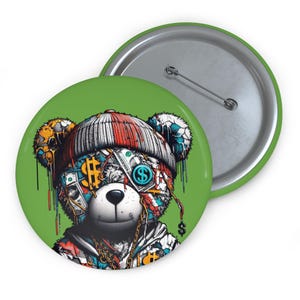 Könnte beinhalten: Ein grüner Button mit einem stilisierten Bären, der eine rot-weiß-schwarze Mütze trägt. Das Gesicht des Bären ist mit Dollarzeichen und Geld bedeckt. Eine goldene Kette liegt um den Hals des Bären. Die Rückseite des Buttons ist silberfarben.