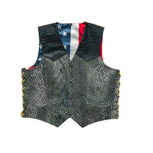 May include: A vest with a snakeskin pattern, black leather shoulders, and a lining featuring the American flag. The vest has gold-colored lacing on the sides and a red lining.